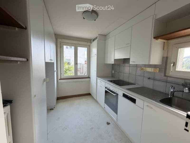 Modern kitchen with white cabinets, stainless steel appliances, and a window offering a view of the outside.