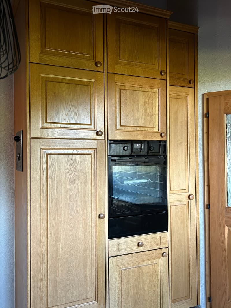 Wooden kitchen cabinets with a built-in oven in the center.