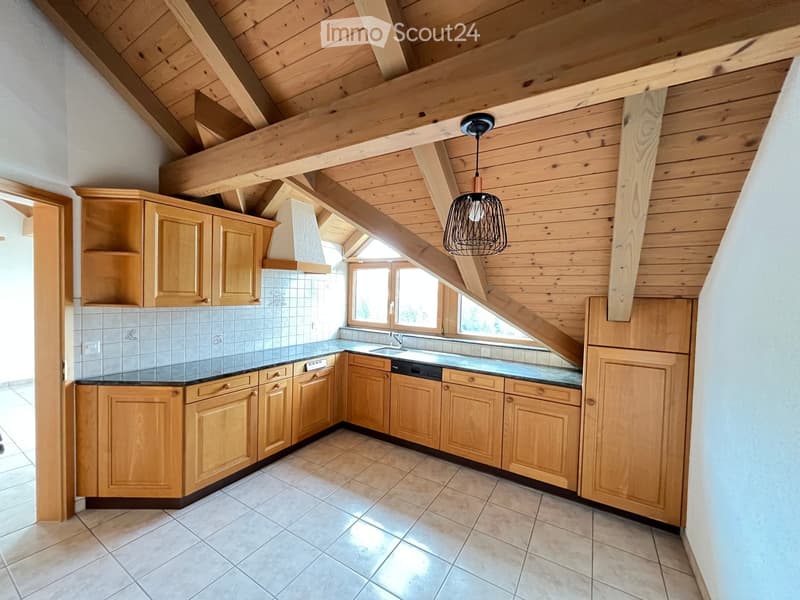 Bright kitchen with wooden cabinets, tiled backsplash, and a modern pendant light fixture. Features a sink, dishwasher, and range hood.