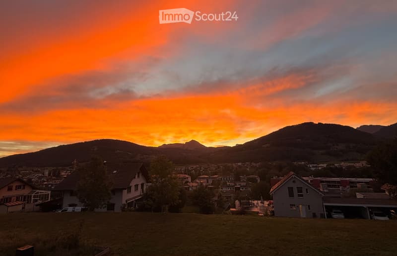 Residential area with houses, garage, and a scenic sunset view of mountains.