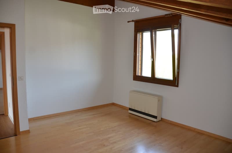 Empty room with wooden flooring, white walls, a window with wooden frame, and a radiator. No furniture or personal items present.