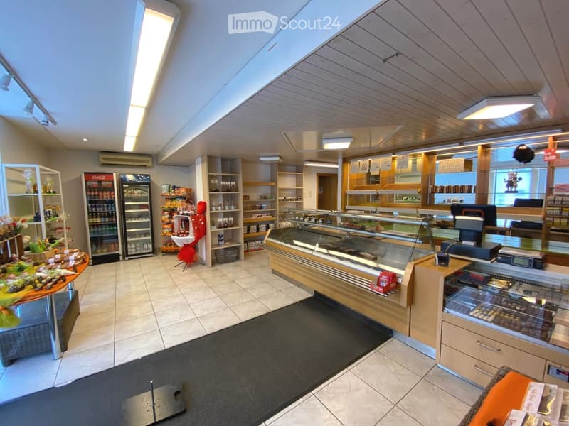 Modern interior with wooden flooring, white walls, shelves, refrigerators, and display cases.