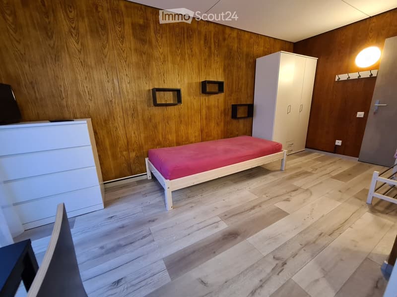 room with wooden wall, bed, white cabinet, wooden floor, shelves, chairs, desk, single bed