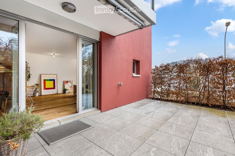 large outdoor patio, terrace with sliding glass door, concrete floor, wall covered in shrubs, view of hills in the distance