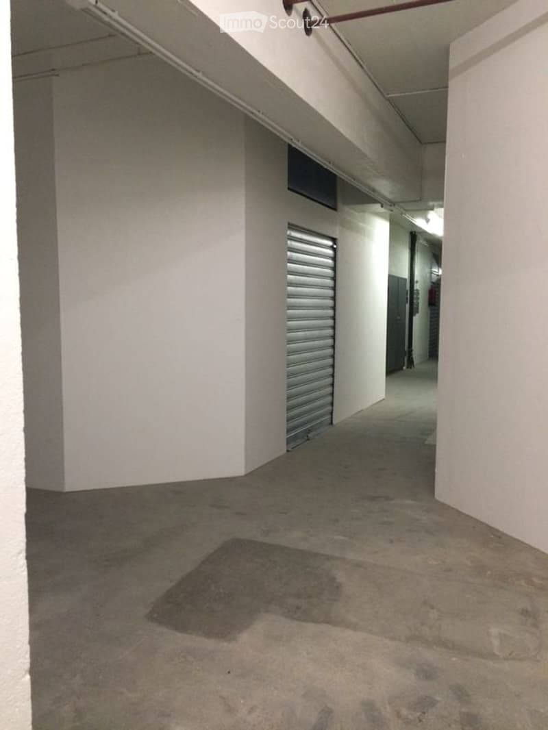 Empty parking lot with white walls, a concrete floor, and a single metal storage unit
