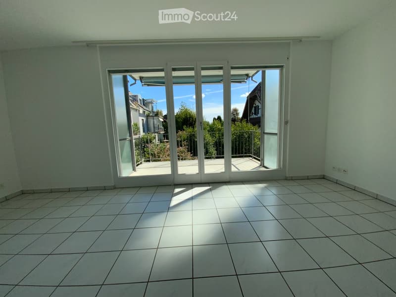 Empty room with white tiled floor and large sliding glass doors leading to a balcony.
