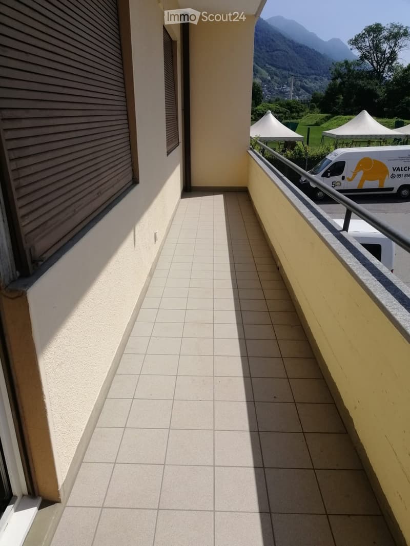Balcony with tiled floor, metal railing, and scenic mountain view in the background.