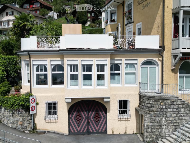 Two-story building with yellow facade, multiple windows, balconies, and a pink garage door.