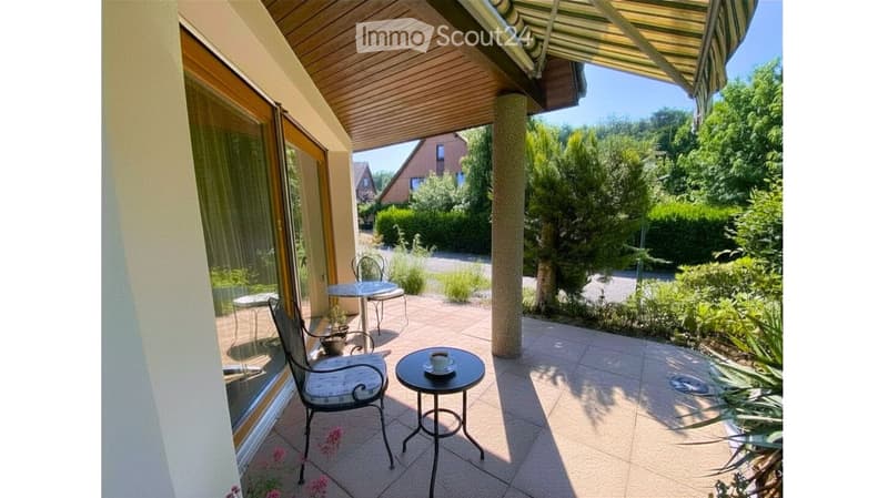 Balcony with tiled floor, covered roof, and outdoor furniture including a chair, small table, and cup.
