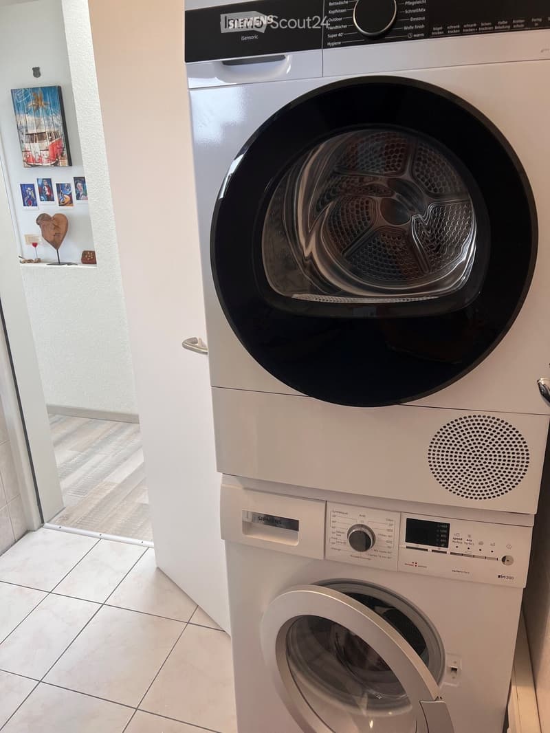 A modern bathroom featuring a Siemens washing machine and dryer unit, with a sleek design and control panel.