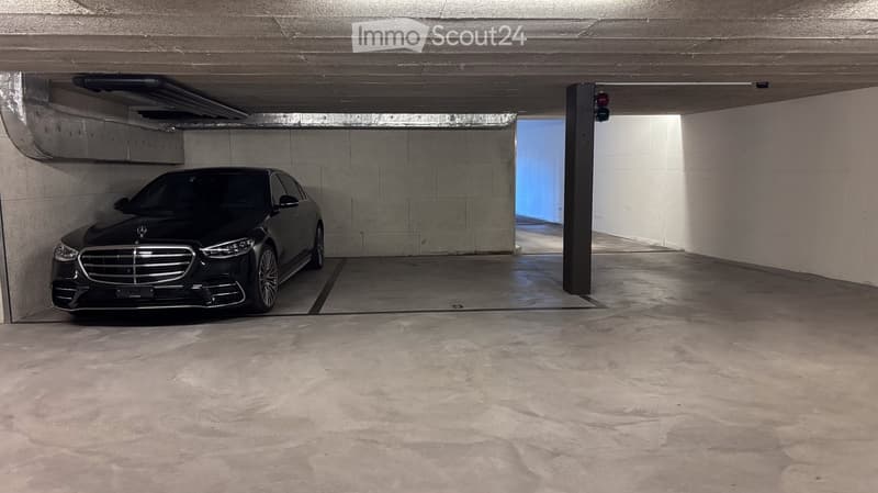 Underground garage with a single parked car, concrete floors, and walls.