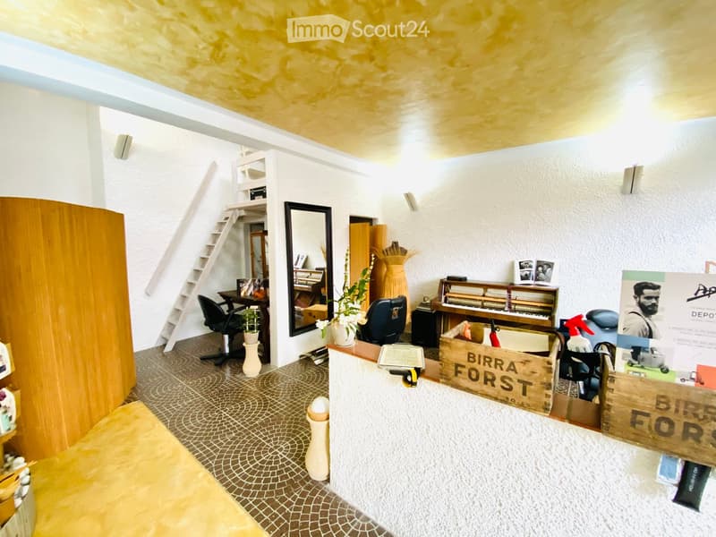 A well-lit room with a mix of modern and rustic elements, including a wooden ladder, a piano, a mirror, and a small seating area.