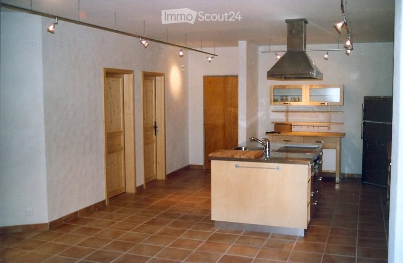 kitchen with island, wooden cabinets, tiled floor, stainless steel appliances, wooden doors, track lighting