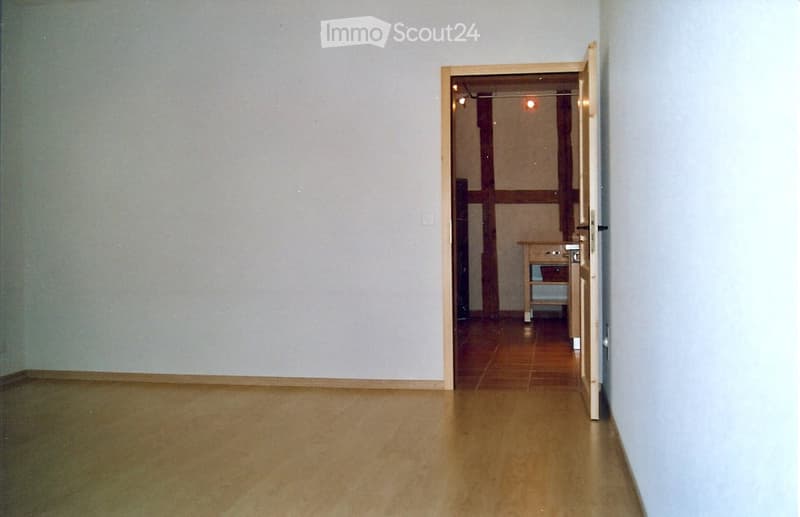 empty room, wooden floor, white walls, open door, small table