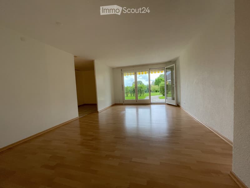 Empty room with wooden flooring, white walls, and large sliding glass doors leading to an outdoor area.