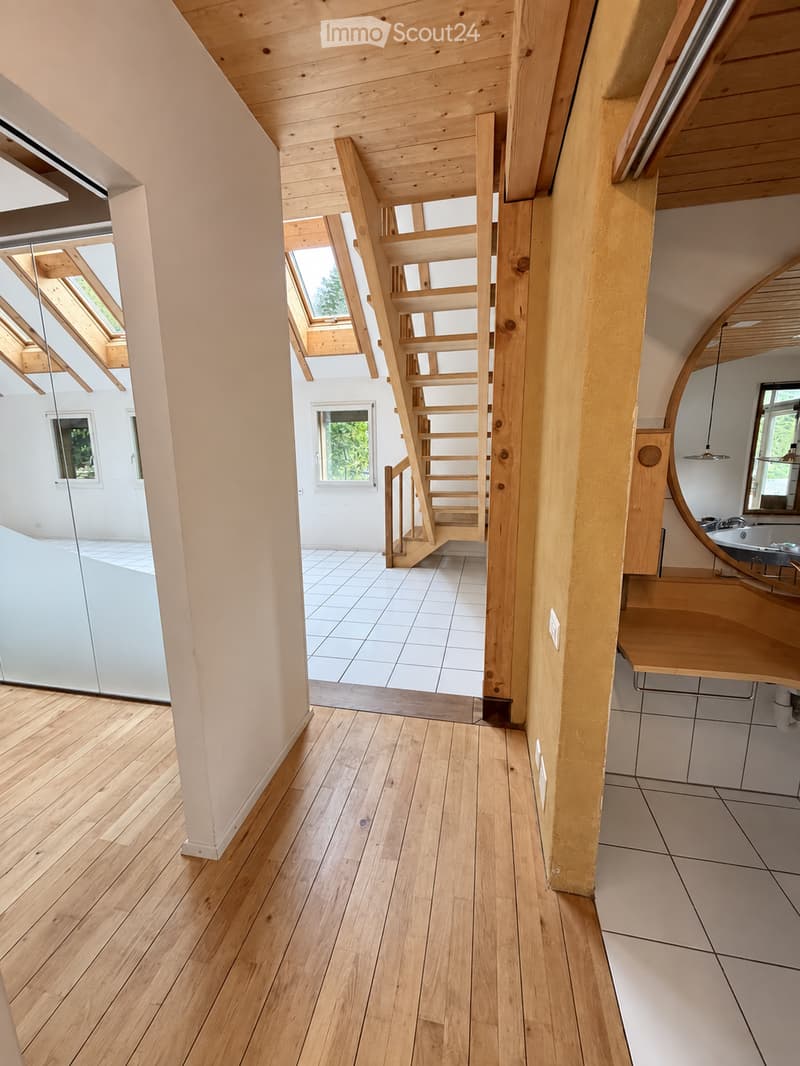 Bright, modern hallway with wooden flooring, white tiled area, staircase leading upwards, and a small bathroom visible to the right.