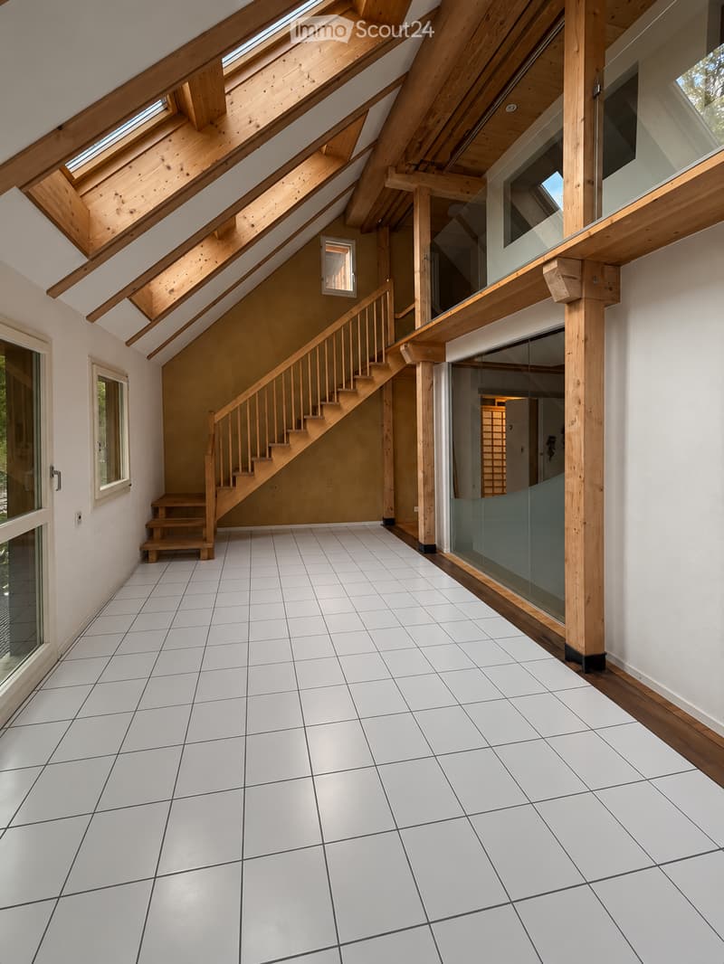 Bright, open hallway with white tiled flooring, wooden staircase leading upwards, large skylights, and glass walls providing natural light.