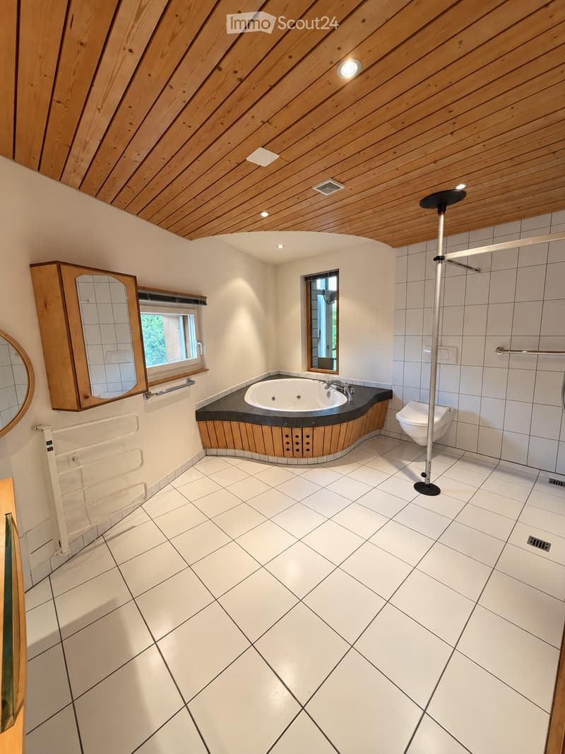 Modern bathroom with white tiled floor and walls, a wooden-framed bathtub, a toilet, a mirror cabinet, and a shower rod.