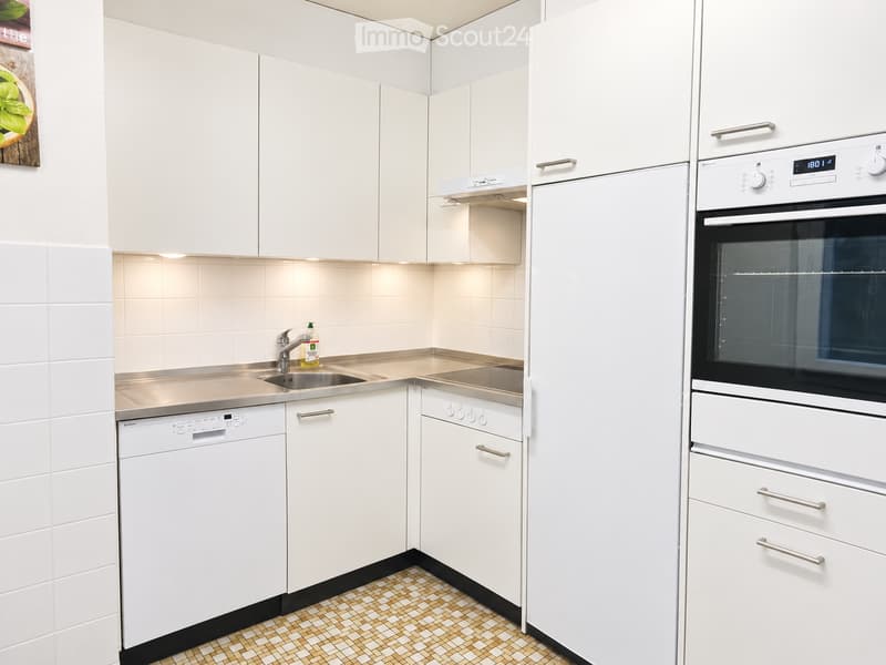 Modern kitchen with white cabinets, stainless steel appliances, and a tiled floor.