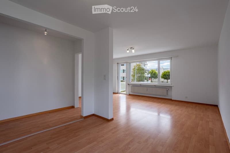 Empty room with light wooden flooring, white walls, and large windows letting in natural light. No furniture or equipment present.