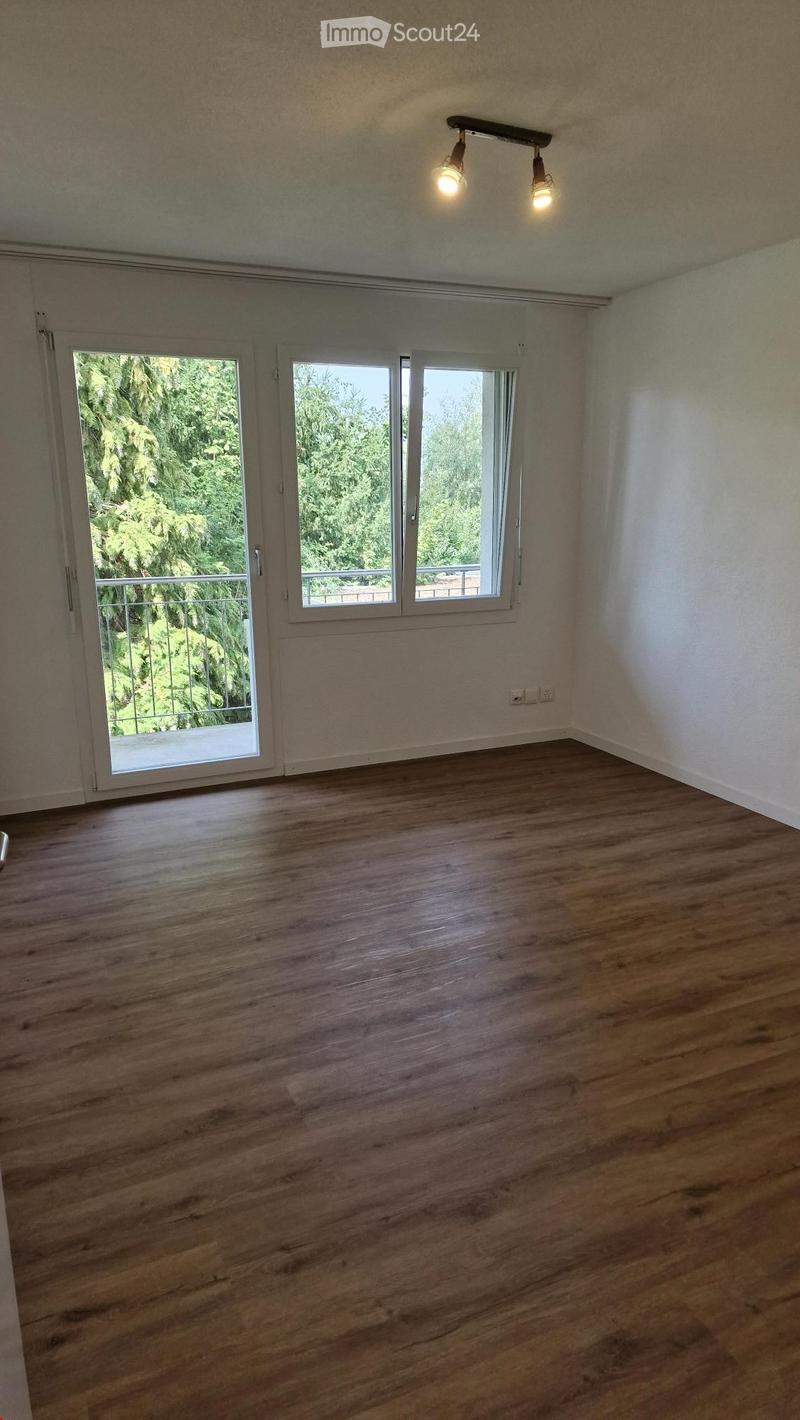 empty room with sliding doors to balcony, wooden floor, white walls