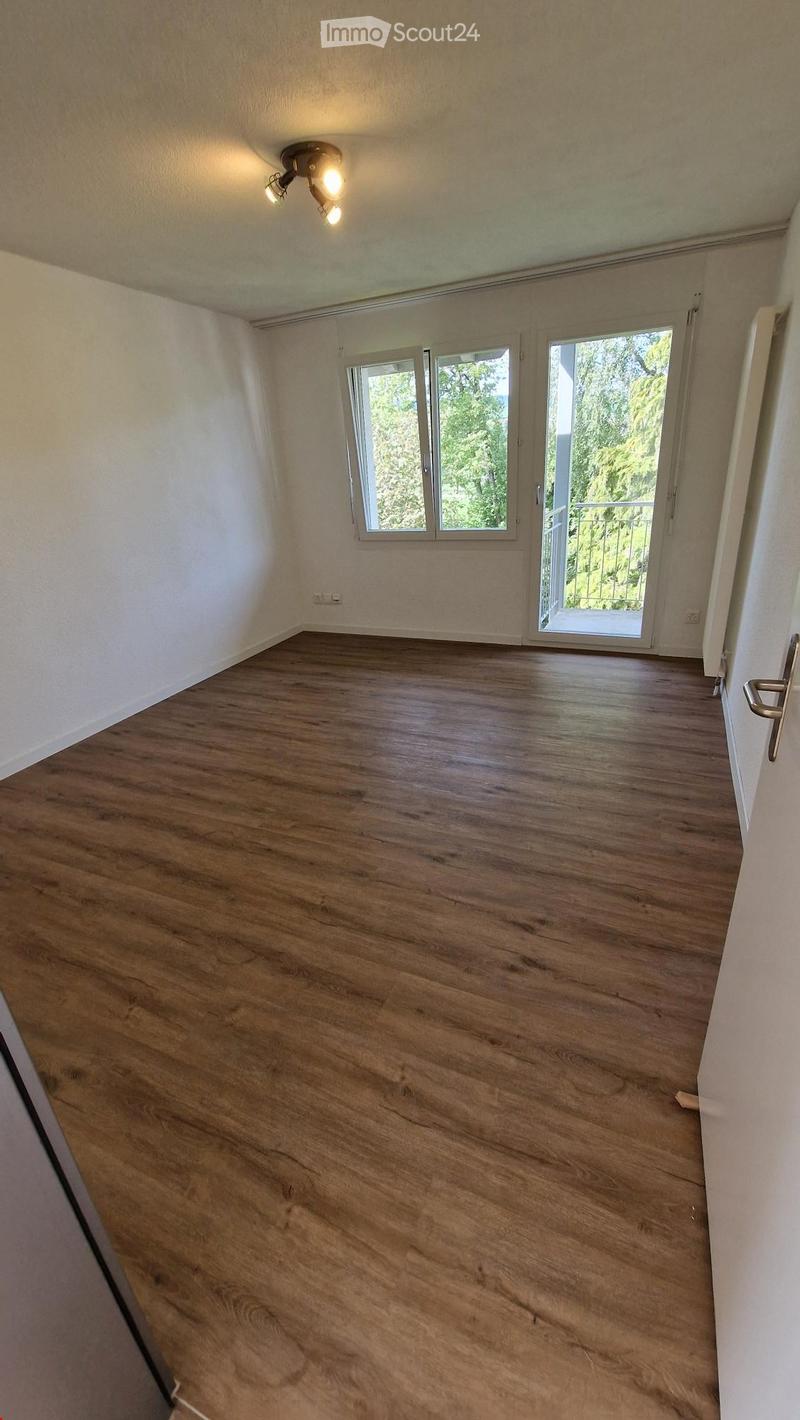 Empty room, wooden floor, sliding glass doors to a balcony, white walls, radiator, ceiling light