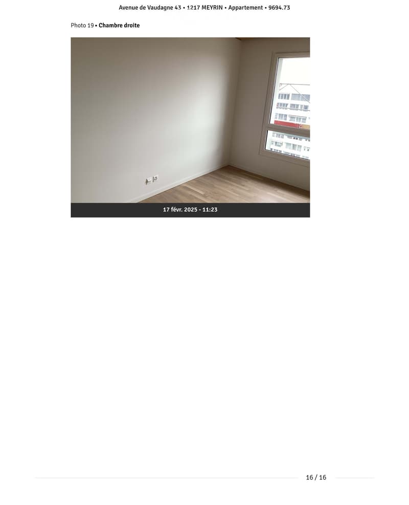 Empty room with light-colored walls, wooden flooring, and a single window showing a view of buildings outside.