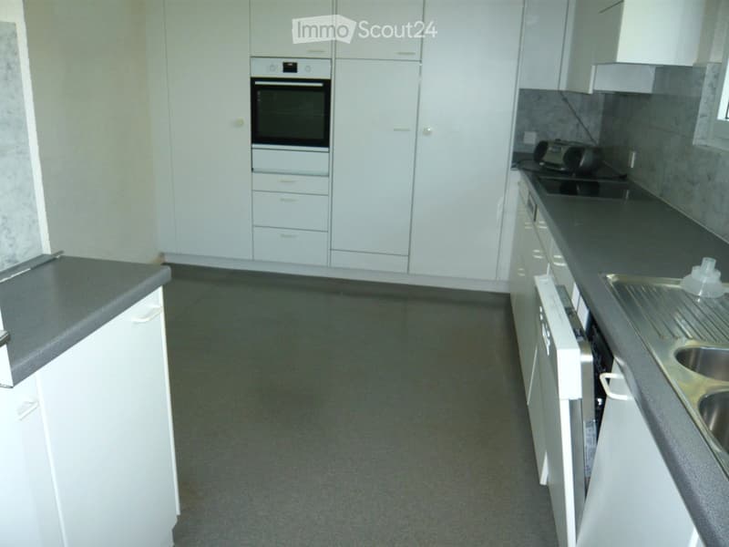 Modern kitchen with white cabinets, stainless steel appliances, and grey countertops.