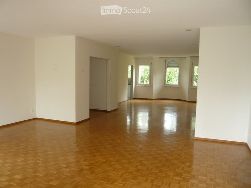 Empty room with polished wooden flooring, white walls, and large windows allowing natural light. No furniture or equipment is present.