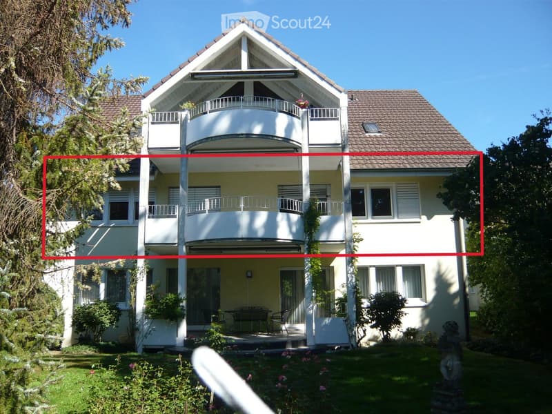 Two-story house with white exterior, multiple balconies, and a well-maintained garden.