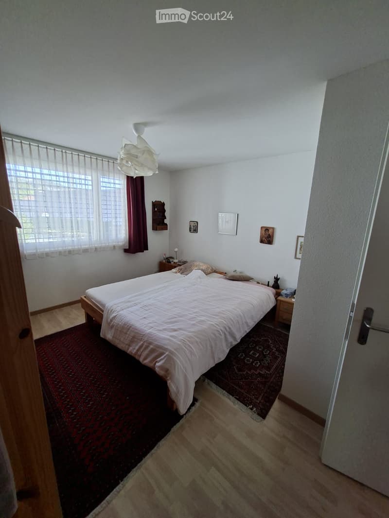 Cozy bedroom with a double bed, nightstand, lamp, and decorative items on the walls.