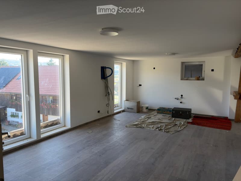 Empty room with wooden flooring, large windows, and a view of the outdoor area. No furniture or equipment is present.