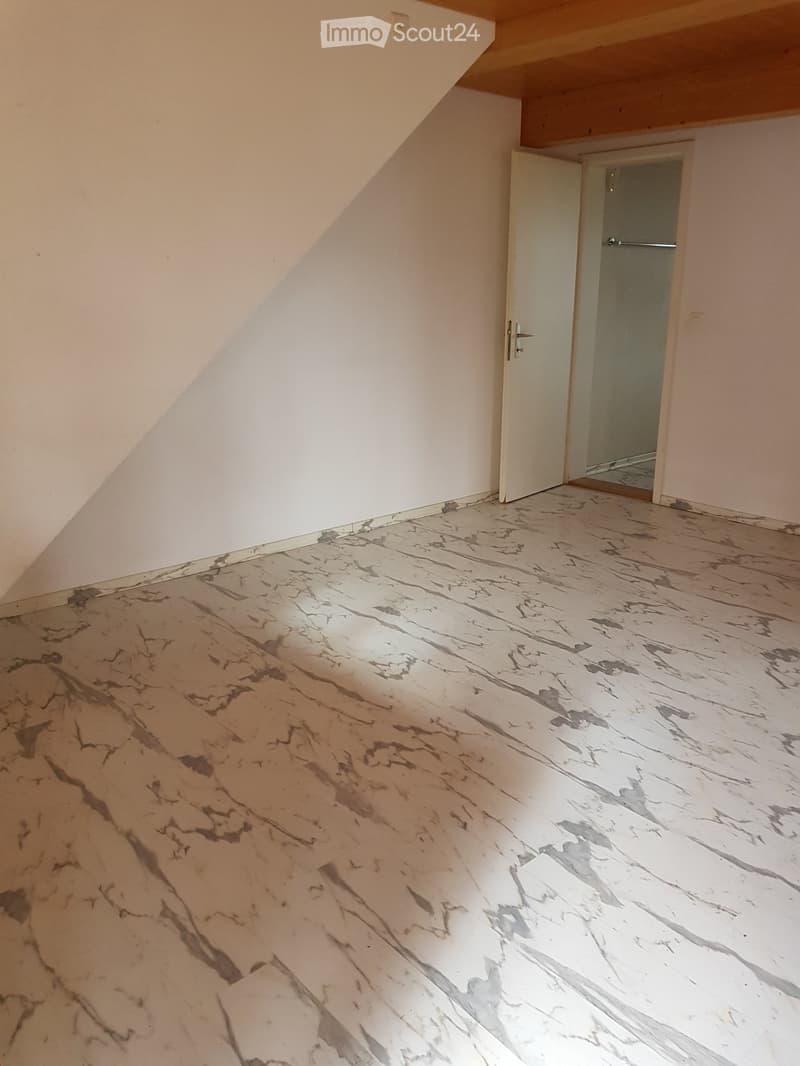 Empty room with marble-patterned flooring and white walls, featuring an open doorway leading to another space.