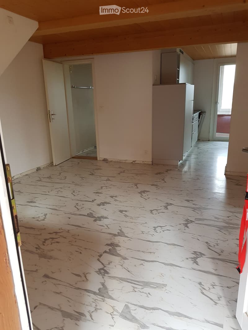 Empty room with marble-patterned flooring, white walls, and open doors leading to other areas.