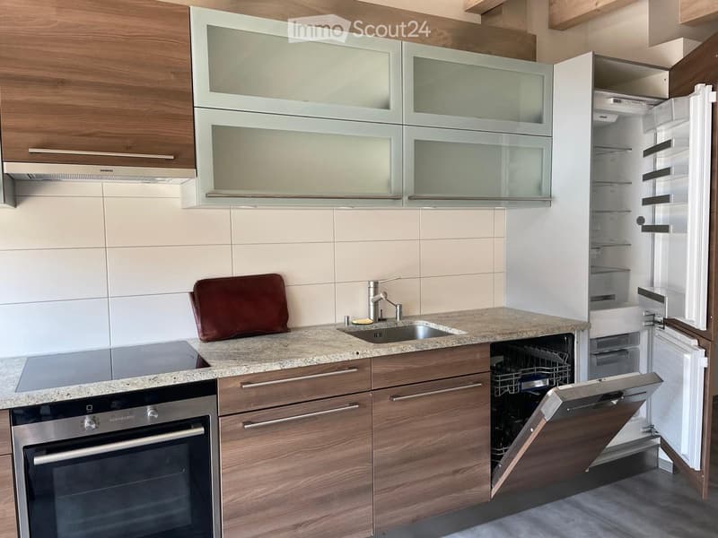 Modern kitchen with wooden cabinets, granite countertop, stainless steel appliances, and a sink with a faucet.