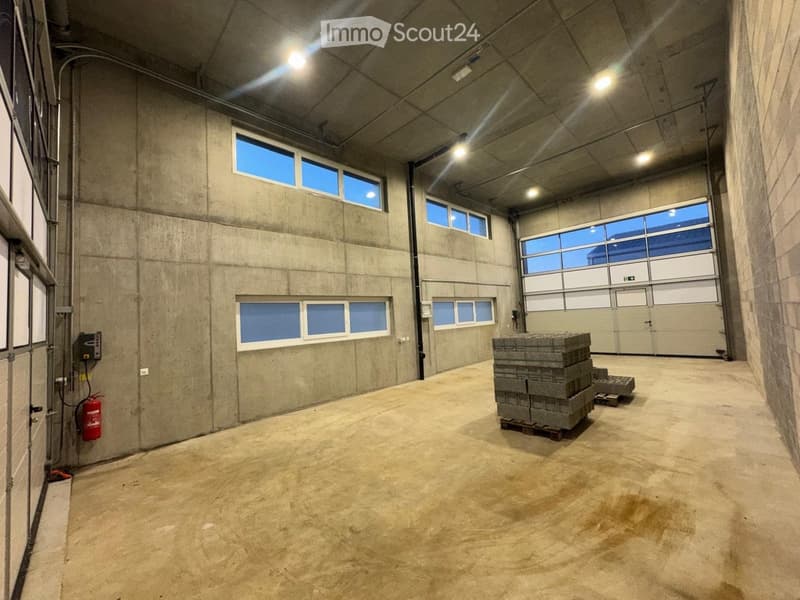 Warehouse: grey concrete walls, double doors, large windows, empty
