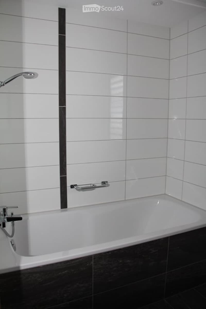 Modern bathroom with a white bathtub, chrome fixtures, and a sleek black accent wall.