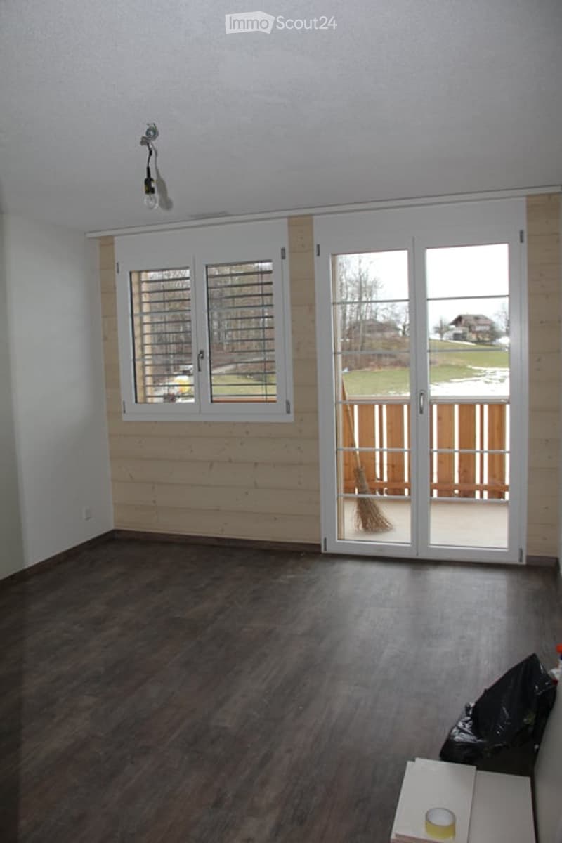 Empty room with wooden flooring, white walls, large sliding glass doors leading to a deck, and a window with blinds. No furniture or equipment present.