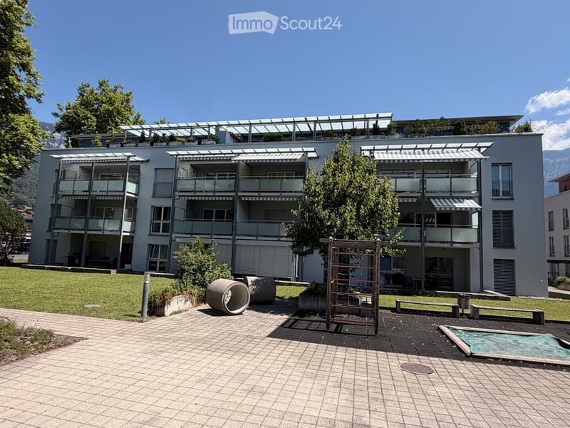 Modern multi-story building with balconies, a rooftop terrace, and a small pool in the foreground.