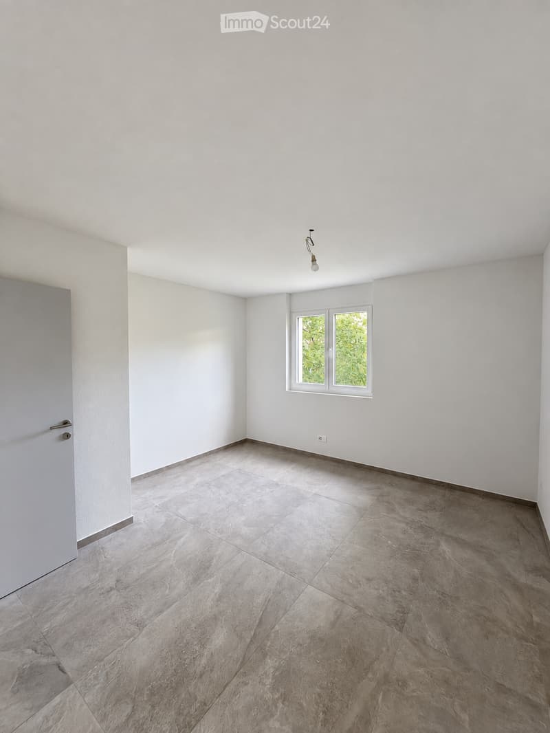 Empty room with light grey tiled floor, white walls, and a single window with white frame. No furniture or equipment present.