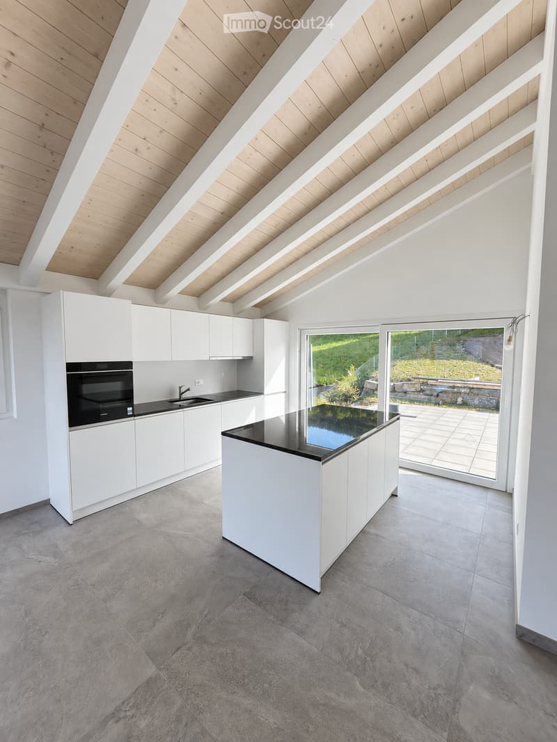 Modern kitchen with white cabinets, a central island, and a black countertop, featuring a sleek design and large windows overlooking a garden.
