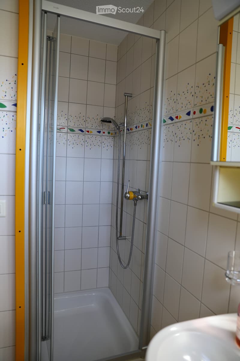 Bathroom with a bathtub, shower area, and tiled walls. Showerhead and faucet are visible.