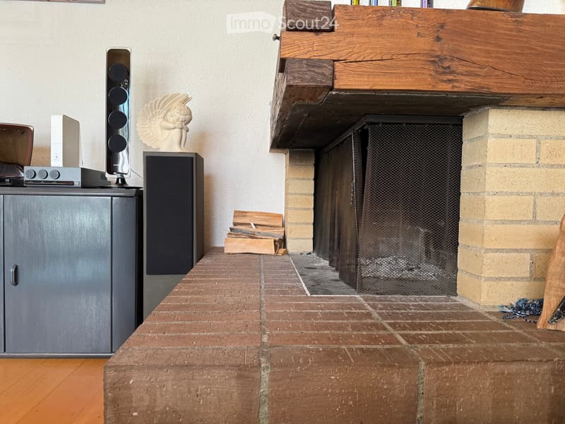 Living room with a brick fireplace, wooden floor, speaker system, cabinet, and decorative sculpture.