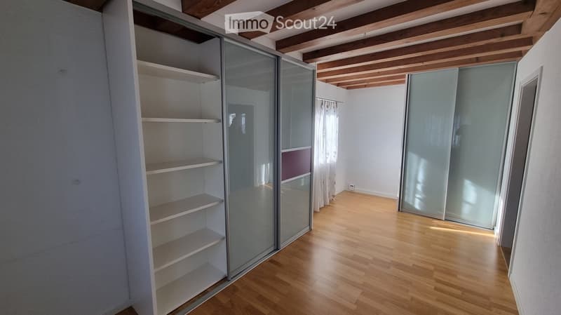 Empty room with wooden flooring, white walls, and built-in shelving unit with glass doors. No furniture or personal items present.