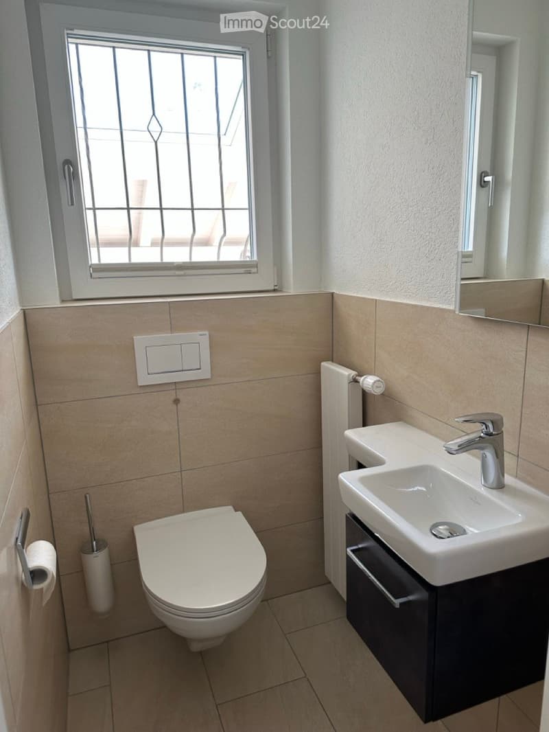 Bathroom with toilet, sink, and a window.