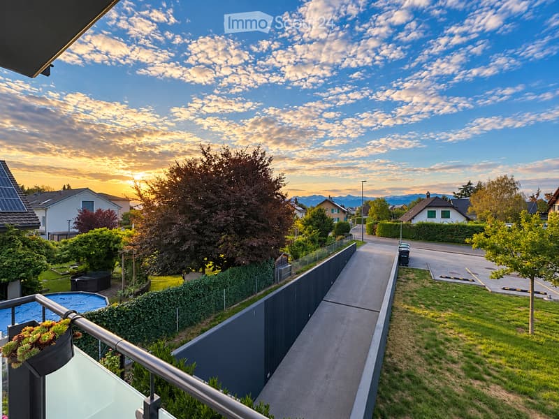 Balcony overlooking a residential neighborhood with a well-maintained garden, a swimming pool, and a pathway leading to the street.