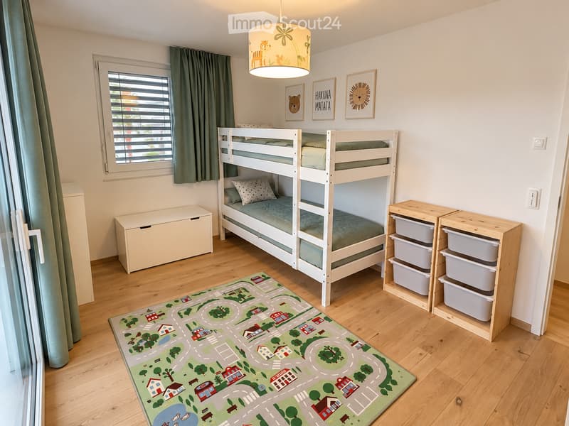 Cozy children's bedroom with a bunk bed, storage unit, colorful rug with road design, and framed artwork on the wall.