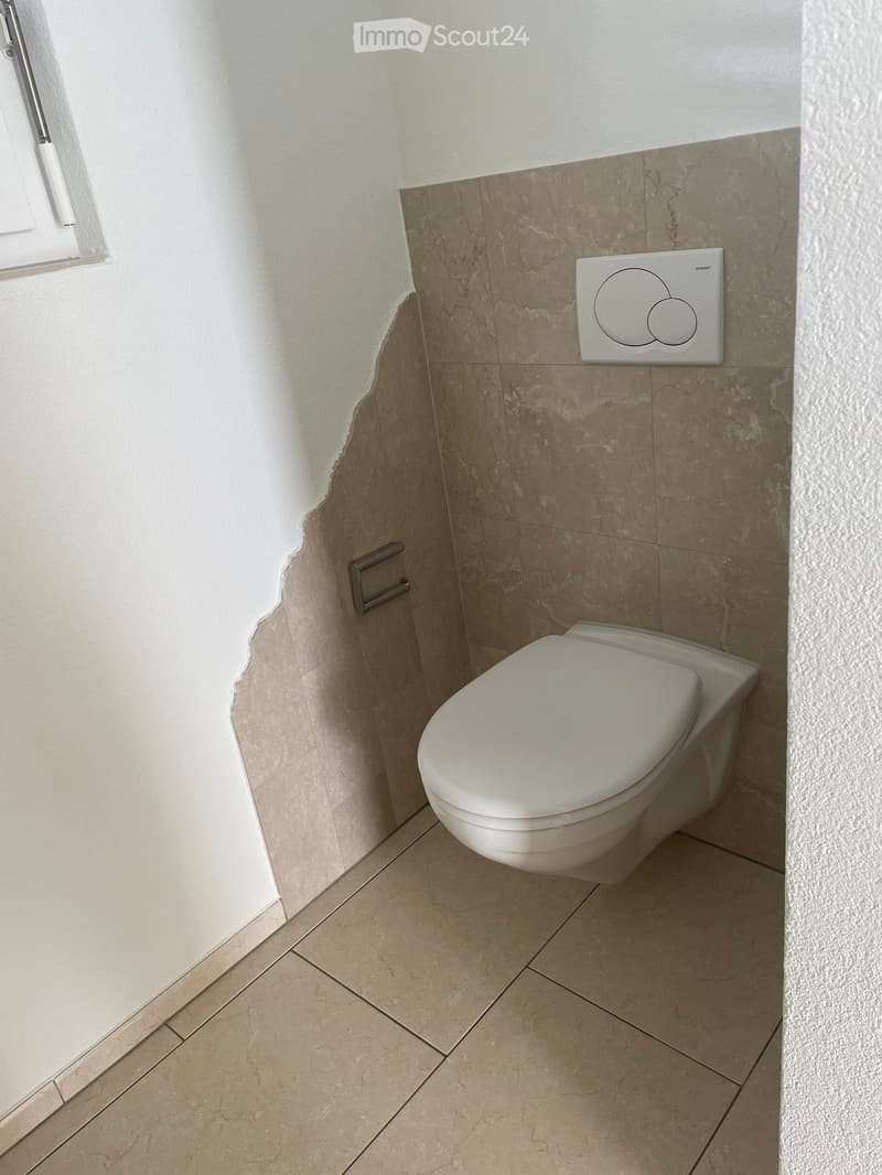 Modern bathroom with beige marble tiles, a toilet, and a control panel mounted on the wall.