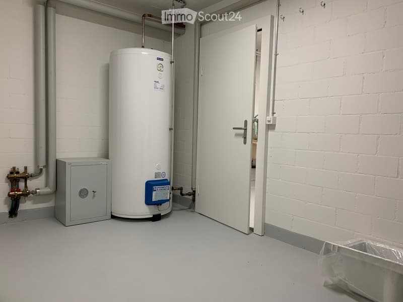 Utility room with white brick walls, a water heater, a grey electrical panel, and a partially open door leading to another room.