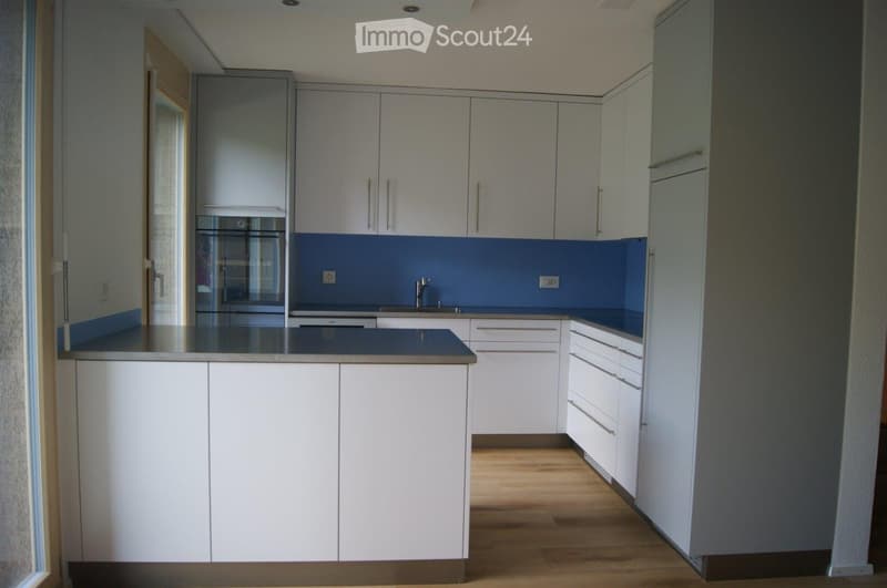 modern kitchen with white cabinets, blue backsplash, stainless steel countertop, built-in oven, dishwasher, and a sink with a faucet